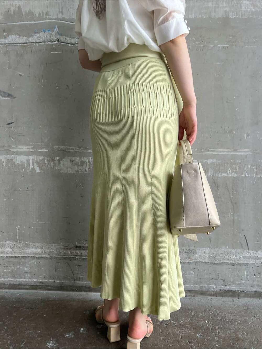 ホワイト系のハンドバッグ、グリーン系のサンダル、イエロー系のスカートを着用したレディースの夏コーディネートの6枚目の写真