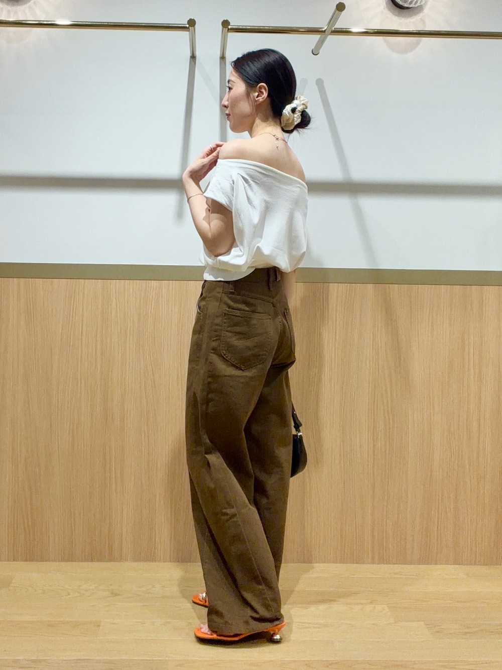 ブラウン系のデニムパンツ、オレンジ系のサンダル、ホワイト系のニット/セーターを着用したレディースの夏コーディネートの2枚目の写真