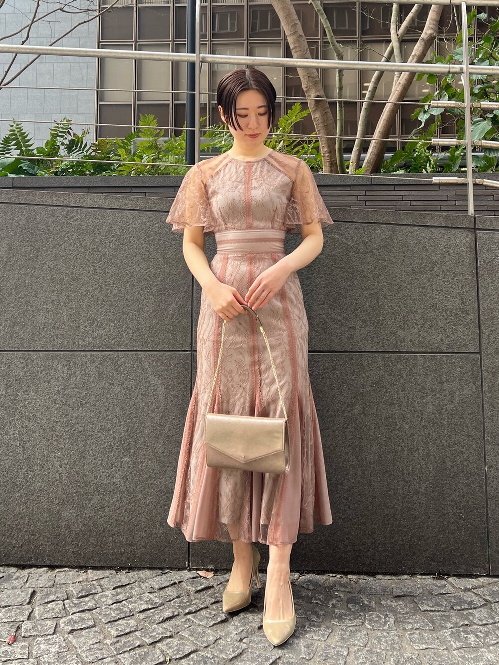 ゴールド系のハンドバッグ、ゴールド系のパンプス、ベージュ系のノーカラーコートを着用したレディースの冬コーディネートの7枚目の写真