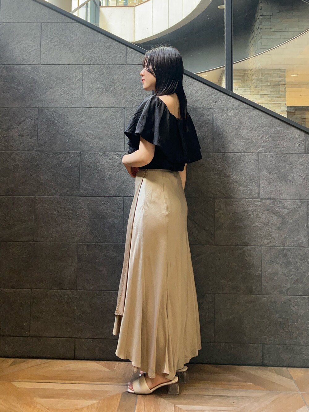 ブラック系のシャツ/ブラウス、ベージュ系のスカート、ホワイト系のサンダルを着用したレディースの夏コーディネートの2枚目の写真