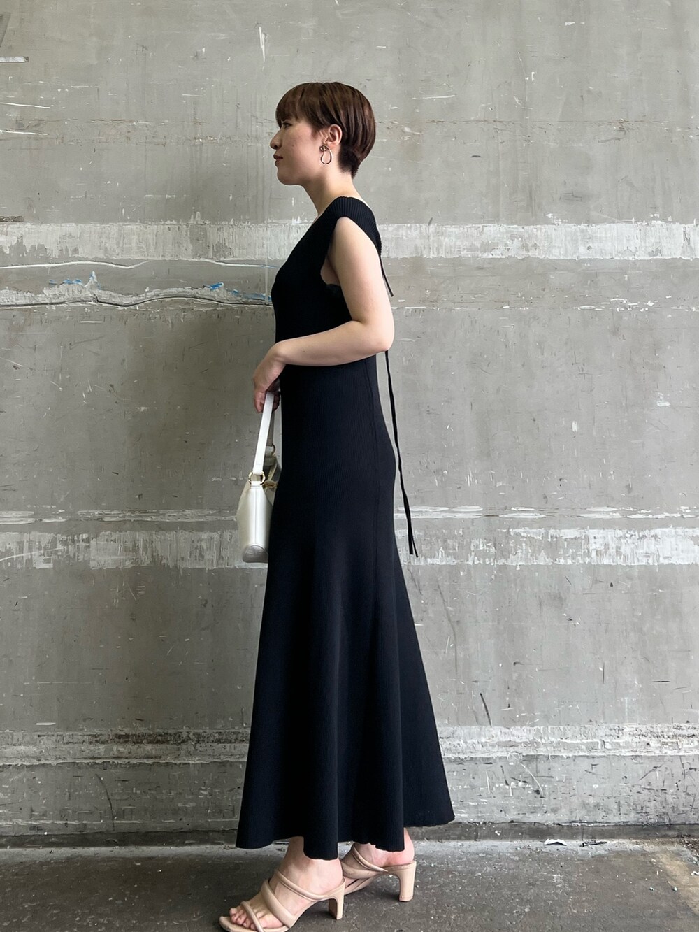 ブラック系のワンピース、ホワイト系のハンドバッグ、ベージュ系のサンダルを着用したレディースの夏コーディネートの2枚目の写真