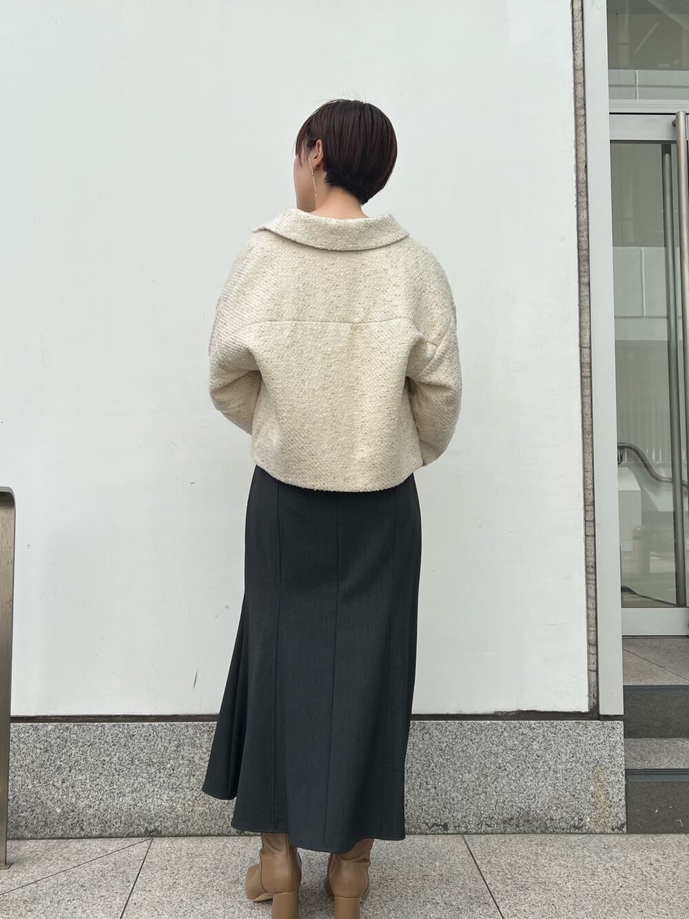 ホワイト系のハンドバッグ、グレー系のスカート、ベージュ系のブーツを着用したレディースの秋コーディネートの2枚目の写真