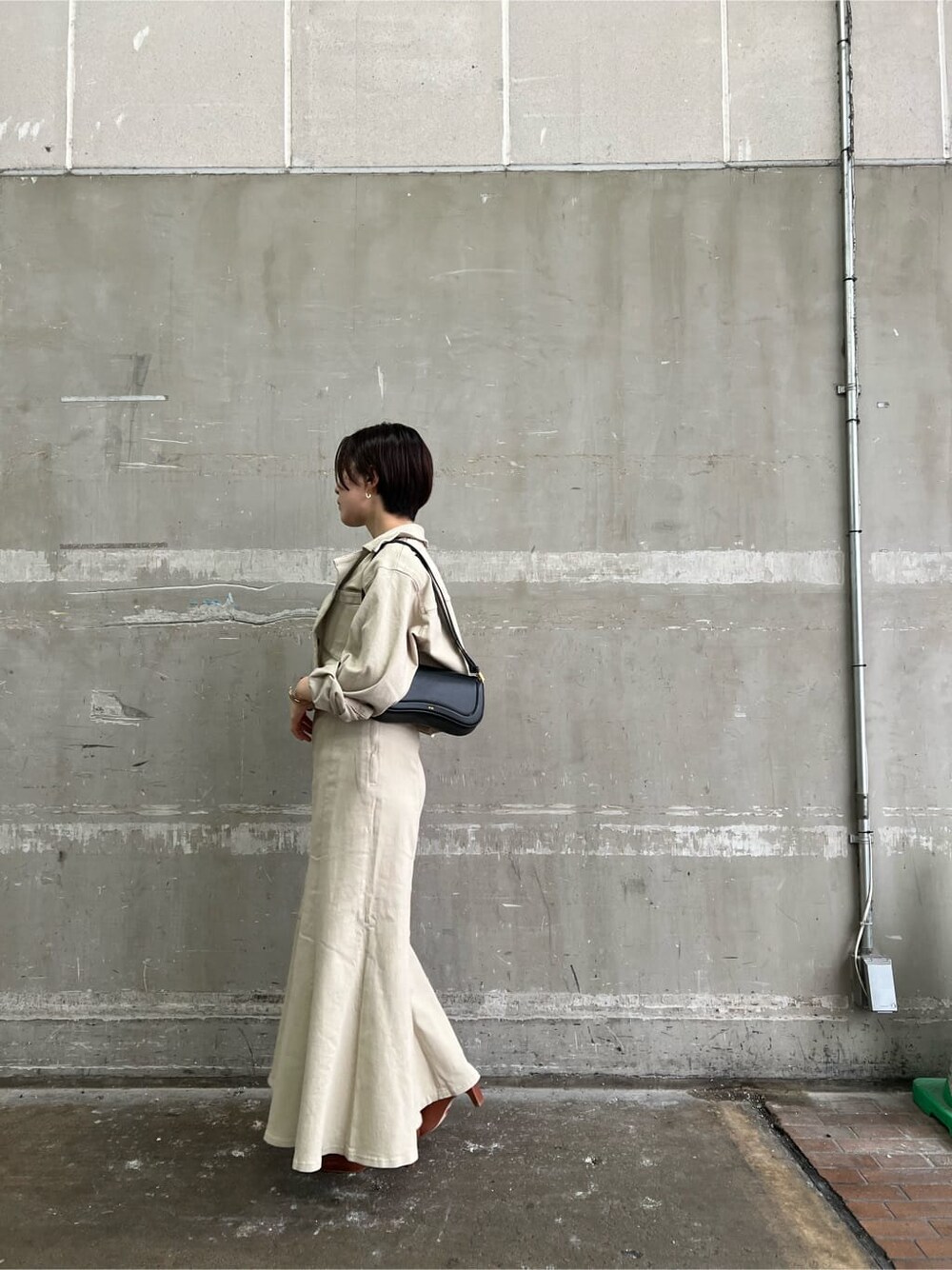 ブラウン系のパンプス、ベージュ系のデニムジャケット、ベージュ系のスカートを着用したレディースの夏コーディネートの2枚目の写真