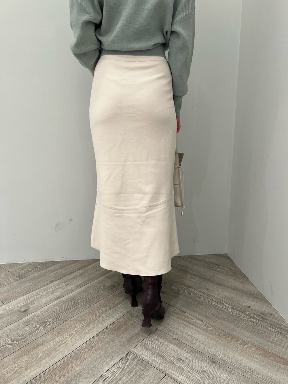 レッド系のブーツ、ホワイト系のハンドバッグ、ホワイト系のスカートを着用したレディースの冬コーディネートの9枚目の写真