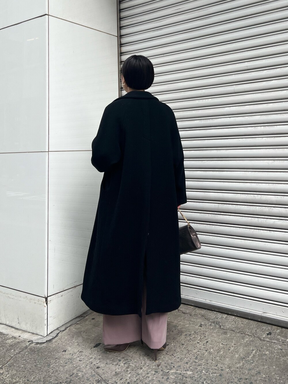 シルバー系のパンプス、ブラック系のチェスターコート、シルバー系のハンドバッグを着用したレディースの冬コーディネートの3枚目の写真