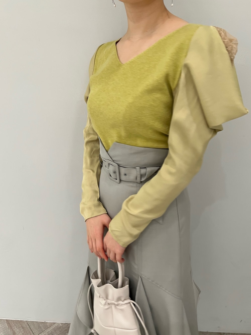 ブラック系のブーツ、ホワイト系のハンドバッグ、グリーン系のスカートを着用したレディースの冬コーディネートの4枚目の写真