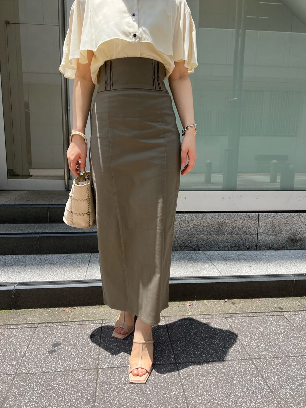 グリーン系のサンダル、ベージュ系のスカート、ホワイト系のショルダーバッグを着用したレディースの夏コーディネートの4枚目の写真