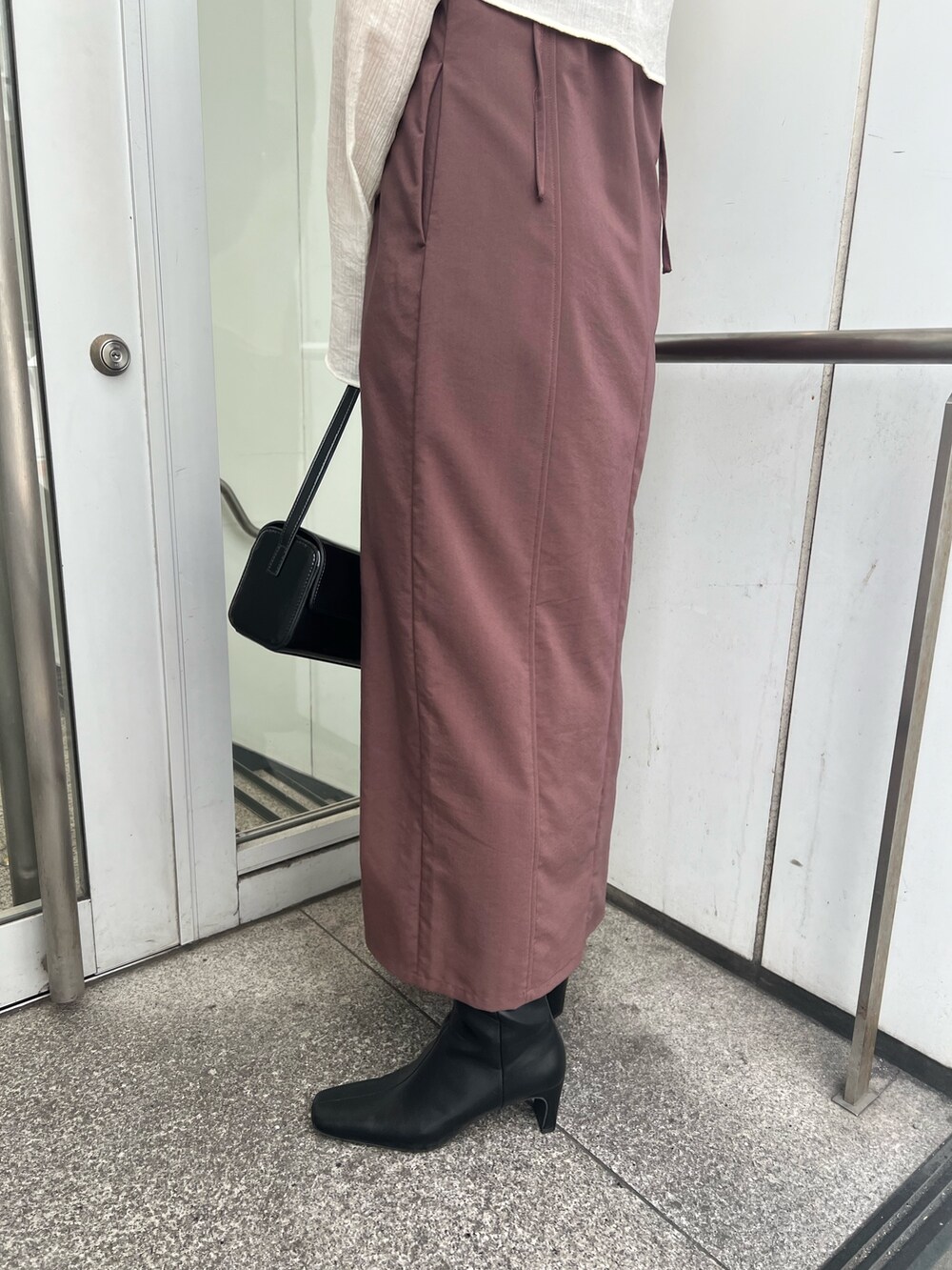 ブラック系のショルダーバッグ、ブラウン系のワンピース、ブラック系のブーツを着用したレディースの秋コーディネートの6枚目の写真