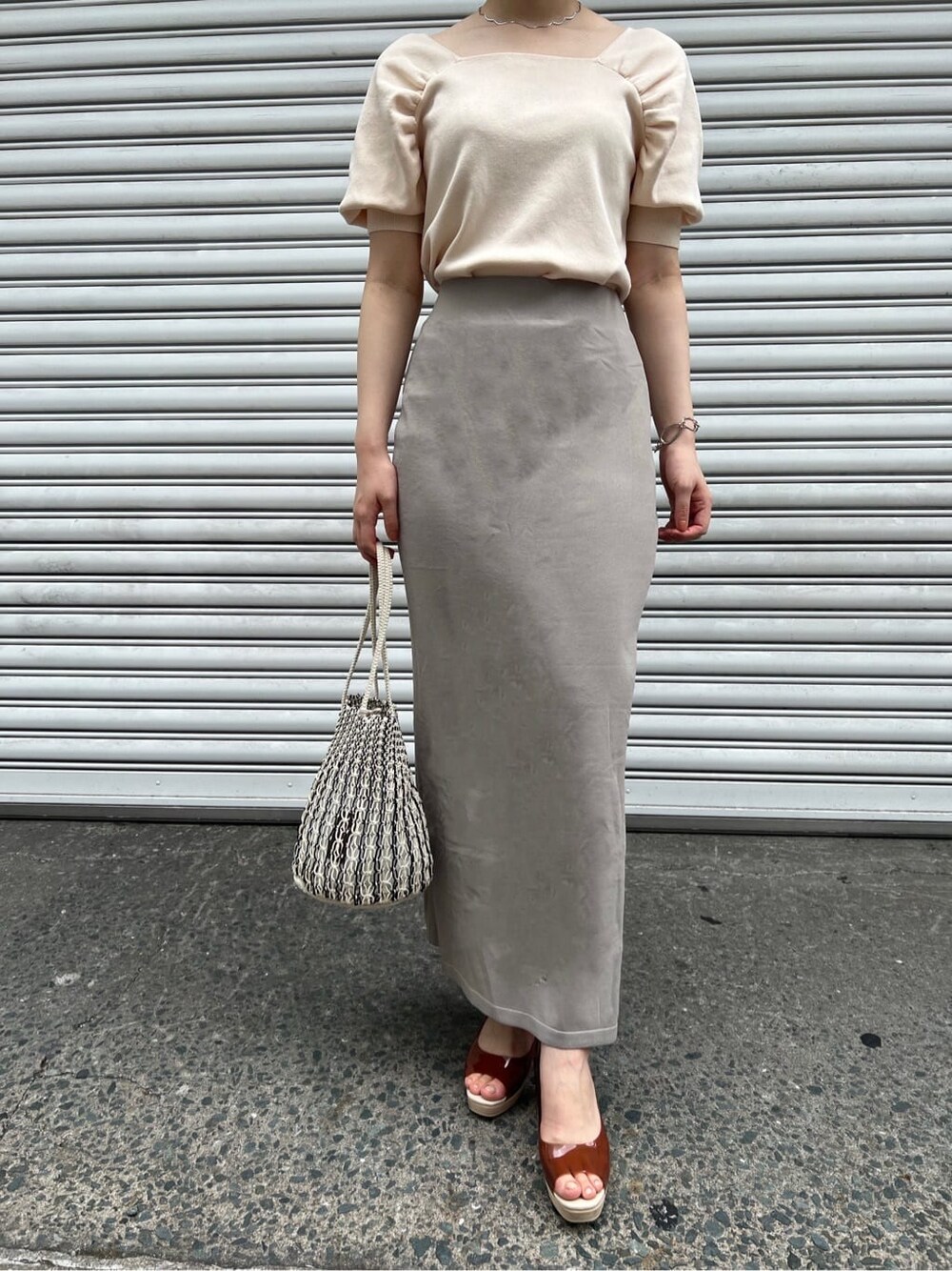 ブラウン系のパンプス、ホワイト系のニット/セーター、ホワイト系のハンドバッグを着用したレディースの夏コーディネートの3枚目の写真