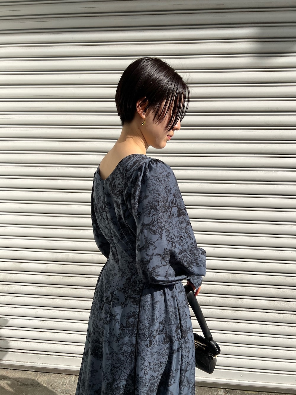 レッド系のブーツ、ブラック系のノーカラーコート、ブルー系のワンピースを着用したレディースの冬コーディネートの6枚目の写真