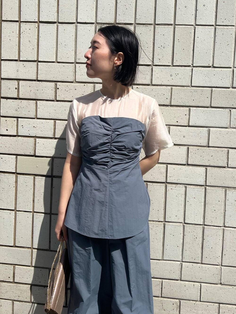 ゴールド系のパンプス、ゴールド系のハンドバッグ、ブルー系のパンツドレスを着用したレディースの春コーディネートの6枚目の写真