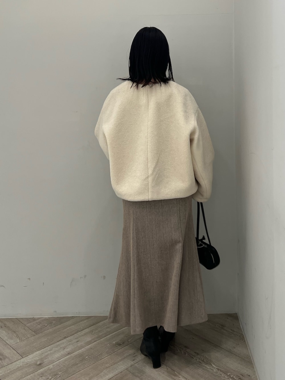 ホワイト系のブルゾン、ベージュ系のジャンパースカート、ブラック系のニット/セーターを着用したレディースの冬コーディネートの3枚目の写真