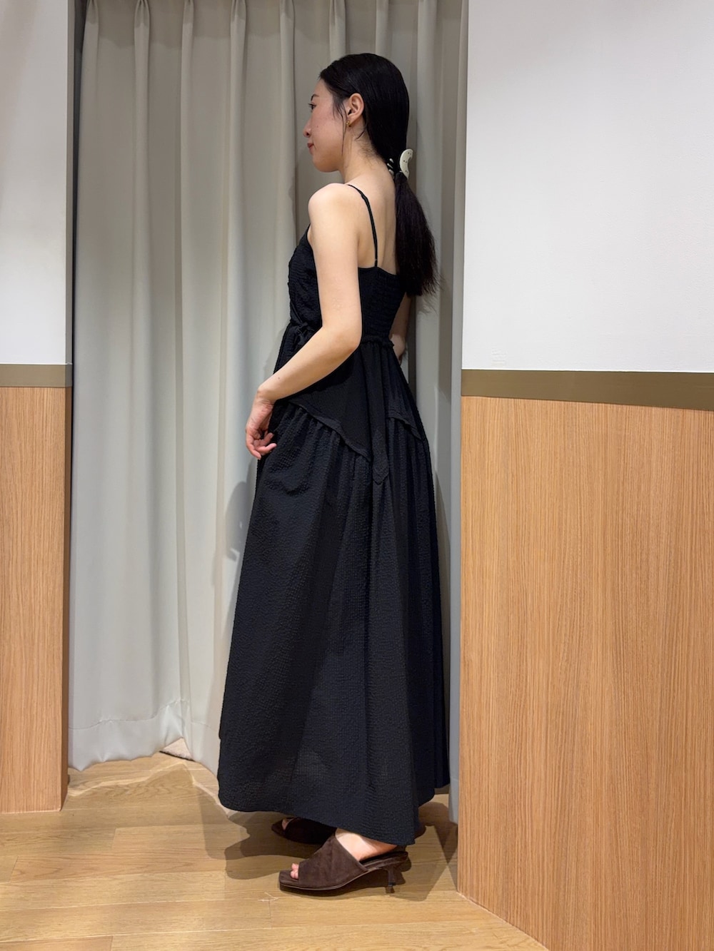 ブラック系のワンピース、ブラウン系のサンダル、ブラック系のハンドバッグを着用したレディースの夏コーディネートの2枚目の写真