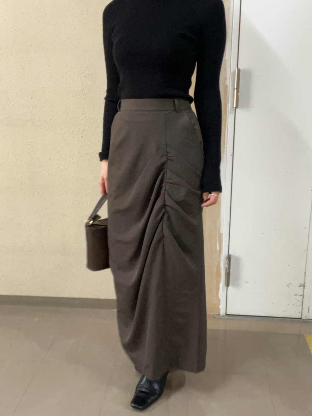 ブラック系のブーツ、ブラック系のニット/セーター、ブラウン系のスカートを着用したレディースの秋コーディネートの5枚目の写真