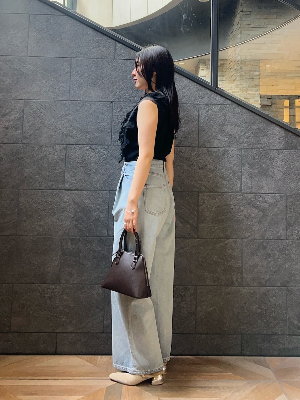 ブラック系のニット/セーター、ベージュ系のパンプス、ブラウン系のボストンバッグを着用したレディースの夏コーディネートの2枚目の写真