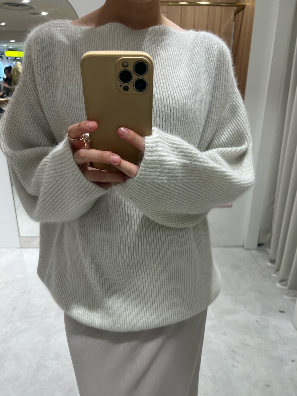 ベージュ系のスニーカー、ホワイト系のニット/セーター、ホワイト系のスカートを着用したレディースの秋コーディネートの6枚目の写真