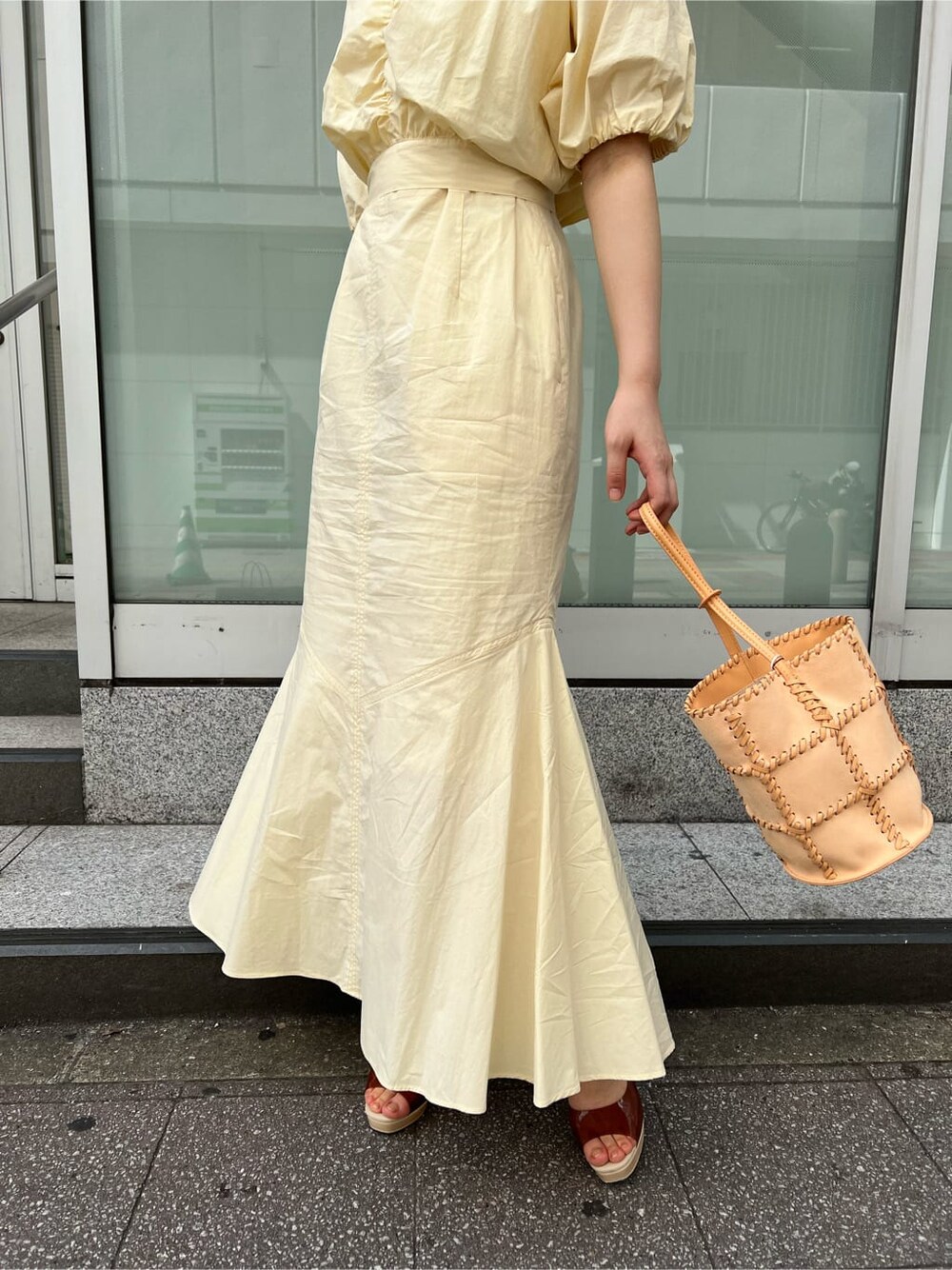 ブルー系のトレンチコート、ブラック系のワンピース、ブラウン系のパンプスを着用したレディースの春コーディネートの9枚目の写真