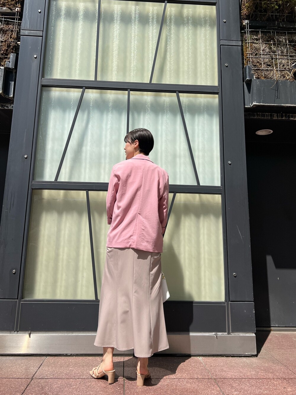 ベージュ系のワンピース、ピンク系のテーラードジャケット、ホワイト系のハンドバッグを着用したレディースの春コーディネートの2枚目の写真