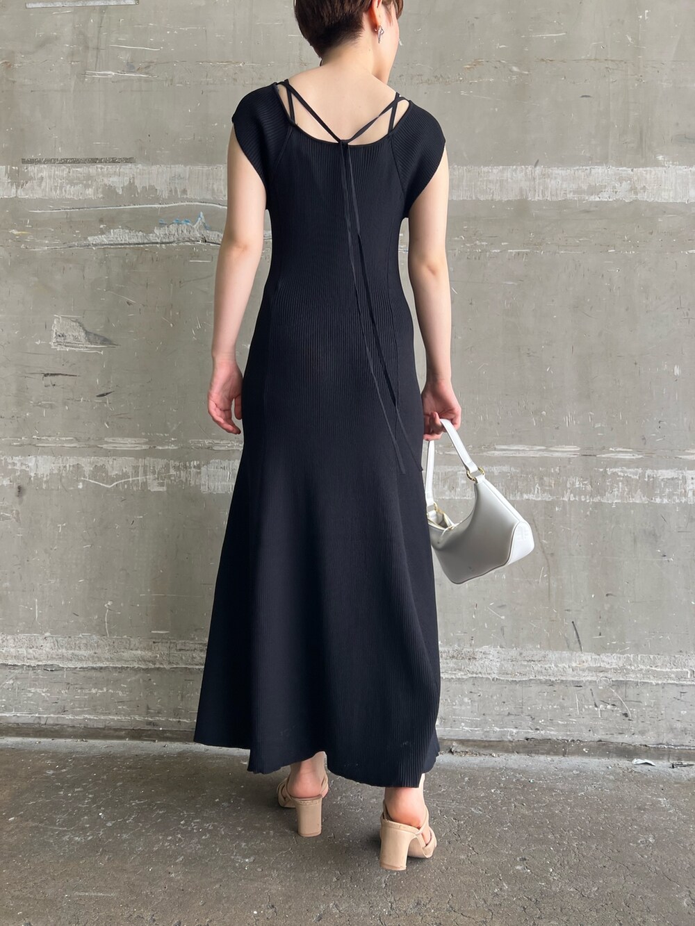 ブラック系のワンピース、ホワイト系のハンドバッグ、ベージュ系のサンダルを着用したレディースの夏コーディネートの7枚目の写真