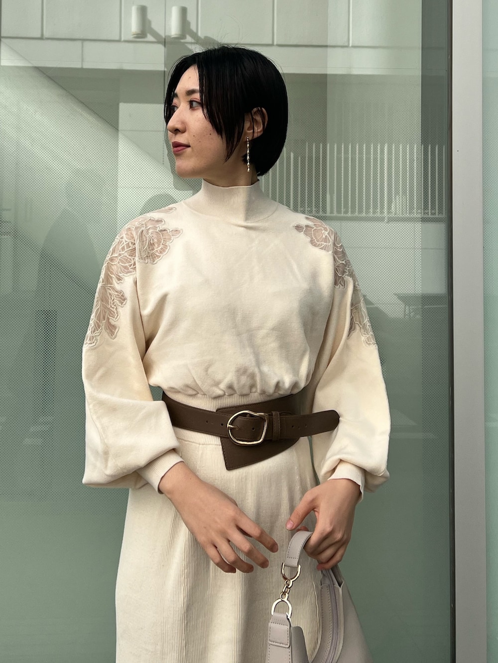 ホワイト系のハンドバッグ、ベージュ系のブーツ、ホワイト系のワンピースを着用したレディースの冬コーディネートの3枚目の写真