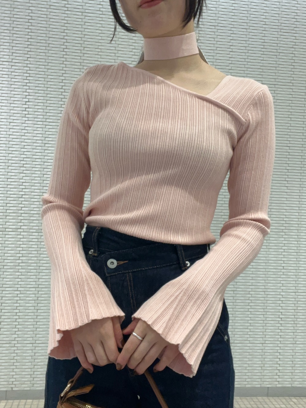 ブルー系のデニムパンツ、ピンク系のニット/セーター、イエロー系のハンドバッグを着用したレディースの冬コーディネートの4枚目の写真