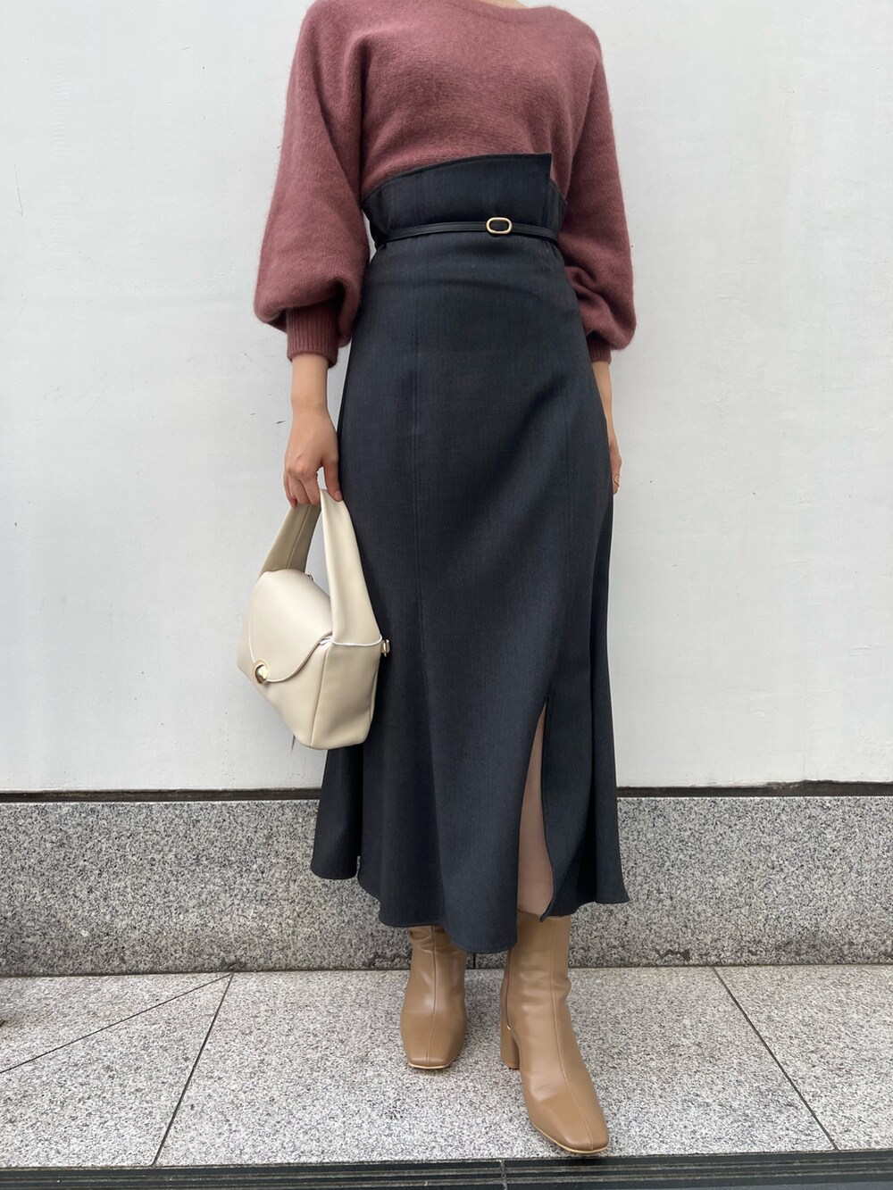 ホワイト系のハンドバッグ、グレー系のスカート、ベージュ系のブーツを着用したレディースの秋コーディネートの9枚目の写真