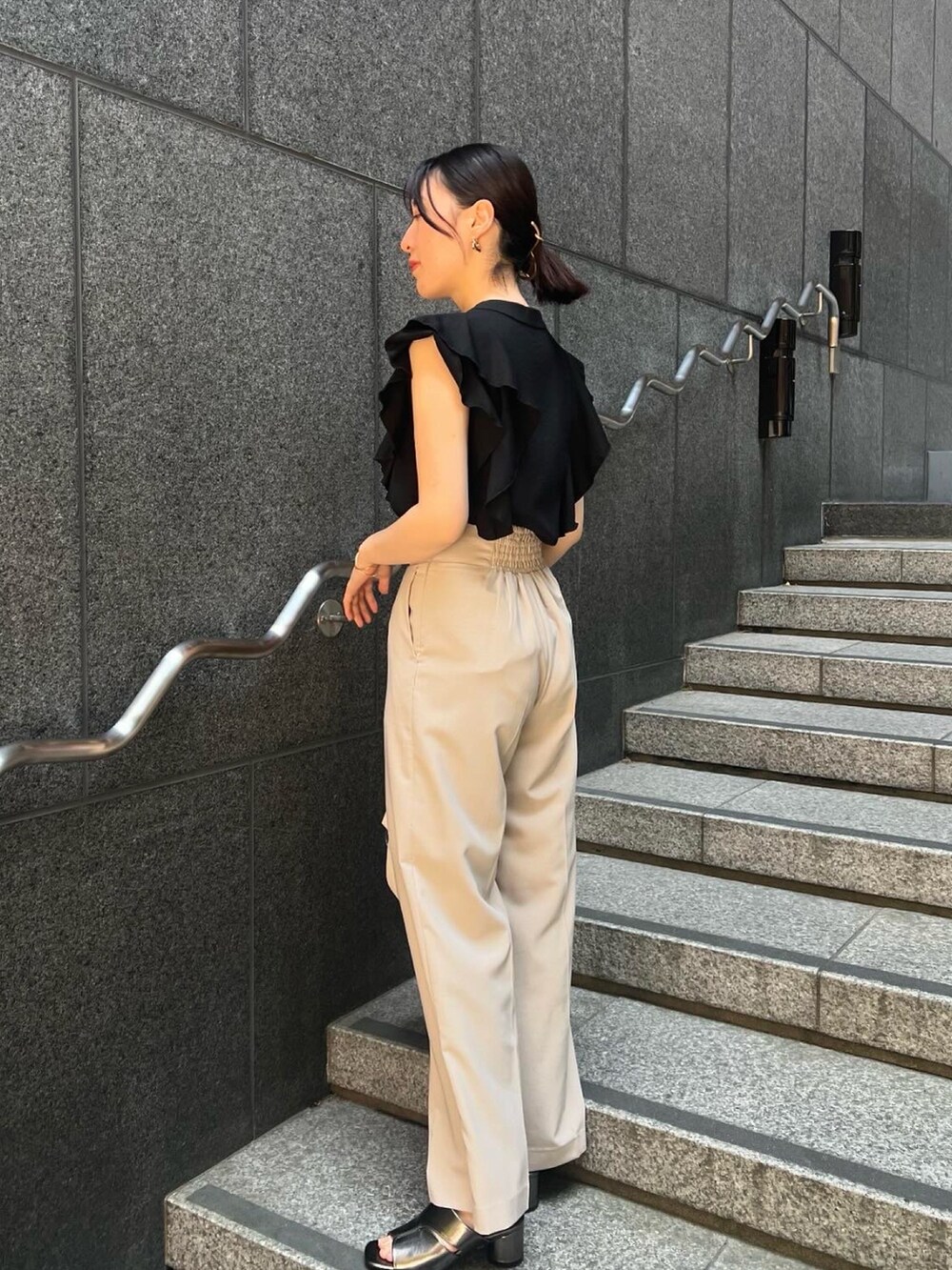 その他のサンダル、ベージュ系のハンドバッグ、ホワイト系のスラックスを着用したレディースの夏コーディネートの2枚目の写真