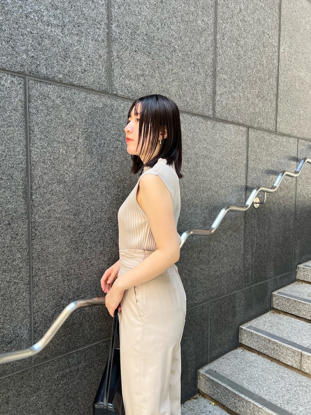 ブラック系のショルダーバッグ、ブラック系のブーツ、ホワイト系のスラックスを着用したレディースの秋コーディネートの6枚目の写真