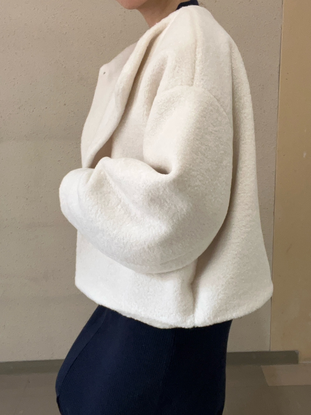 ホワイト系のブルゾン、ブルー系のワンピース、ブラック系のブーツを着用したレディースの秋コーディネートの5枚目の写真