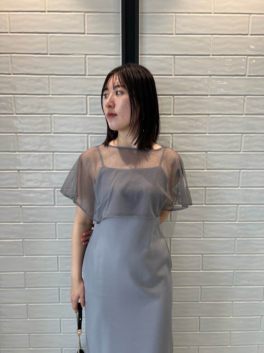 パープル系のドレス、ブラック系のクラッチバッグ、ブラック系のパンプスを着用したレディースの秋コーディネートの2枚目の写真