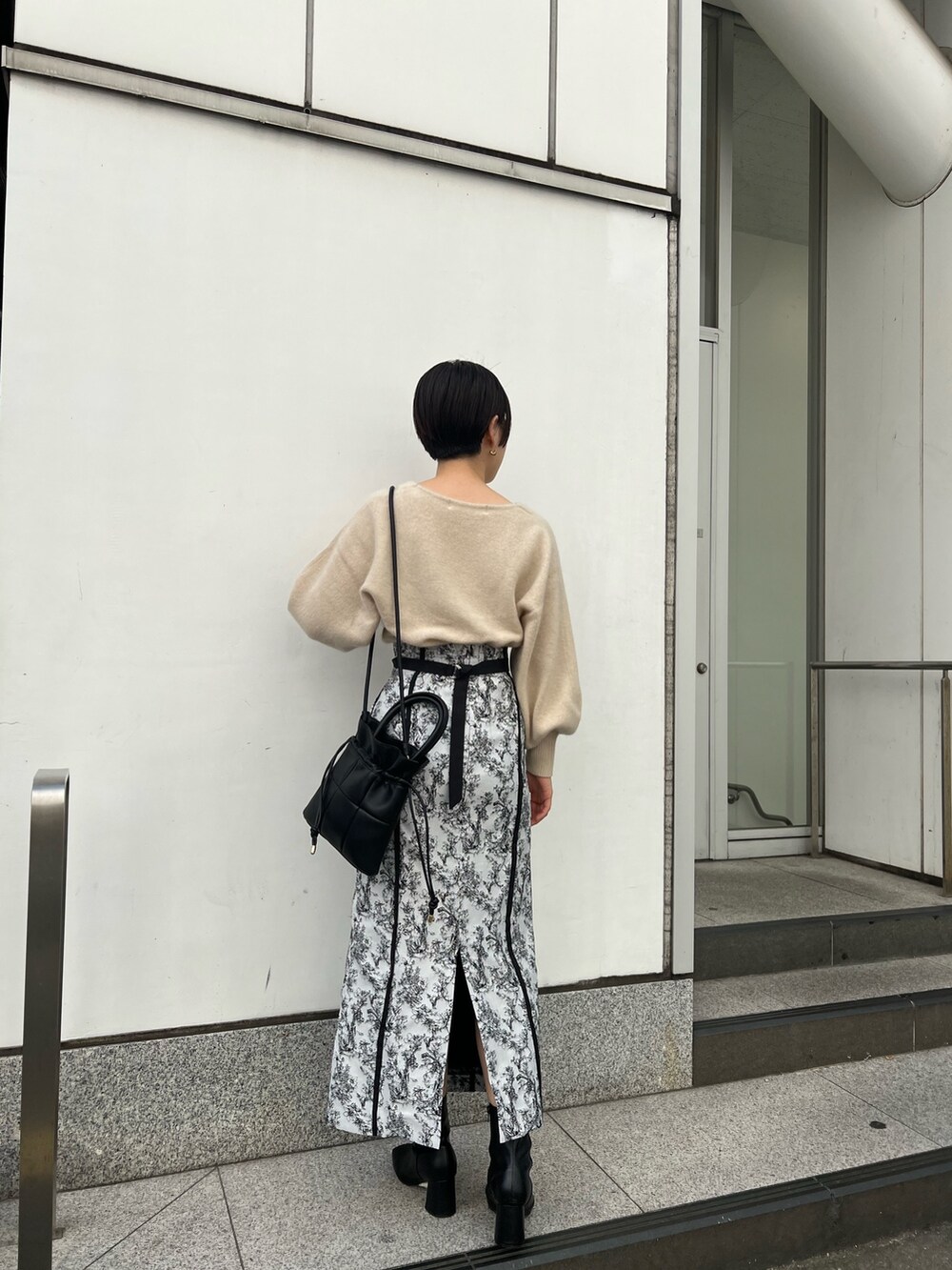 ブラック系のブーツ、ブラック系のスカート、グレー系のカーディガン/ボレロを着用したレディースの秋コーディネートの6枚目の写真