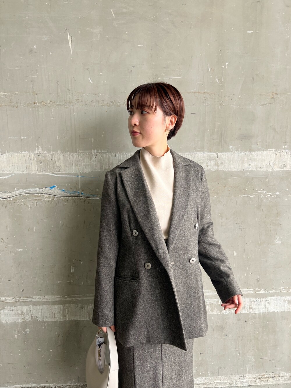 ブラウン系のスカート、ブラウン系のテーラードジャケット、ホワイト系のハンドバッグを着用したレディースの秋コーディネートの4枚目の写真