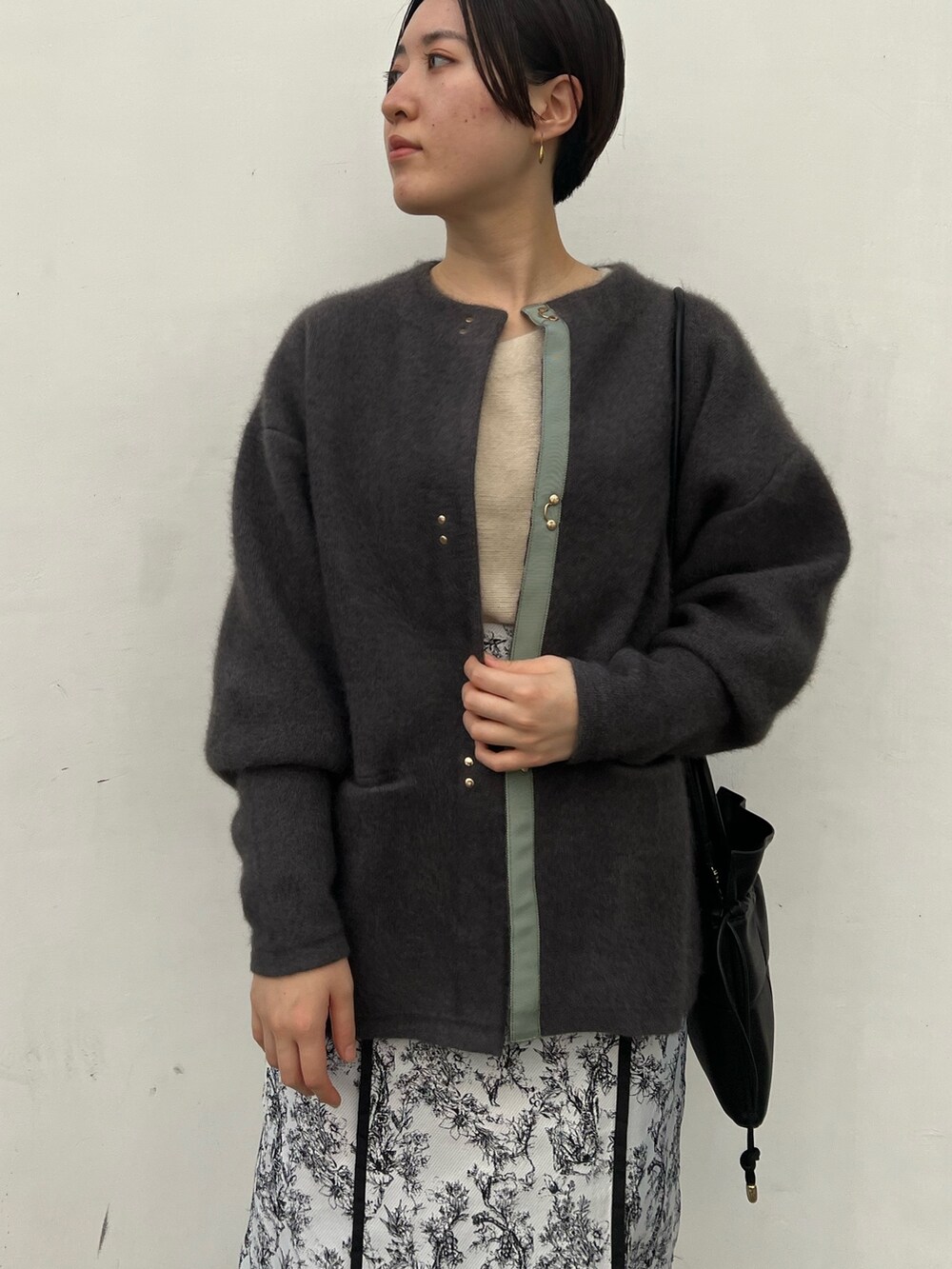 ブラック系のブーツ、ブラック系のスカート、グレー系のカーディガン/ボレロを着用したレディースの秋コーディネートの2枚目の写真