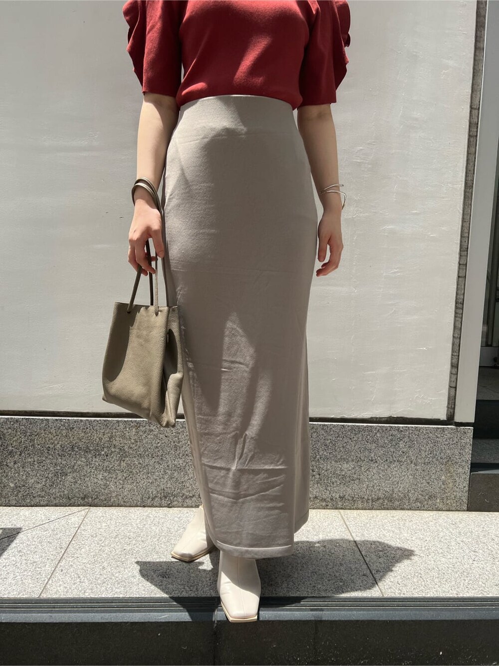 ベージュ系のハンドバッグ、ホワイト系のサンダル、ベージュ系のスカートを着用したレディースの夏コーディネートの9枚目の写真