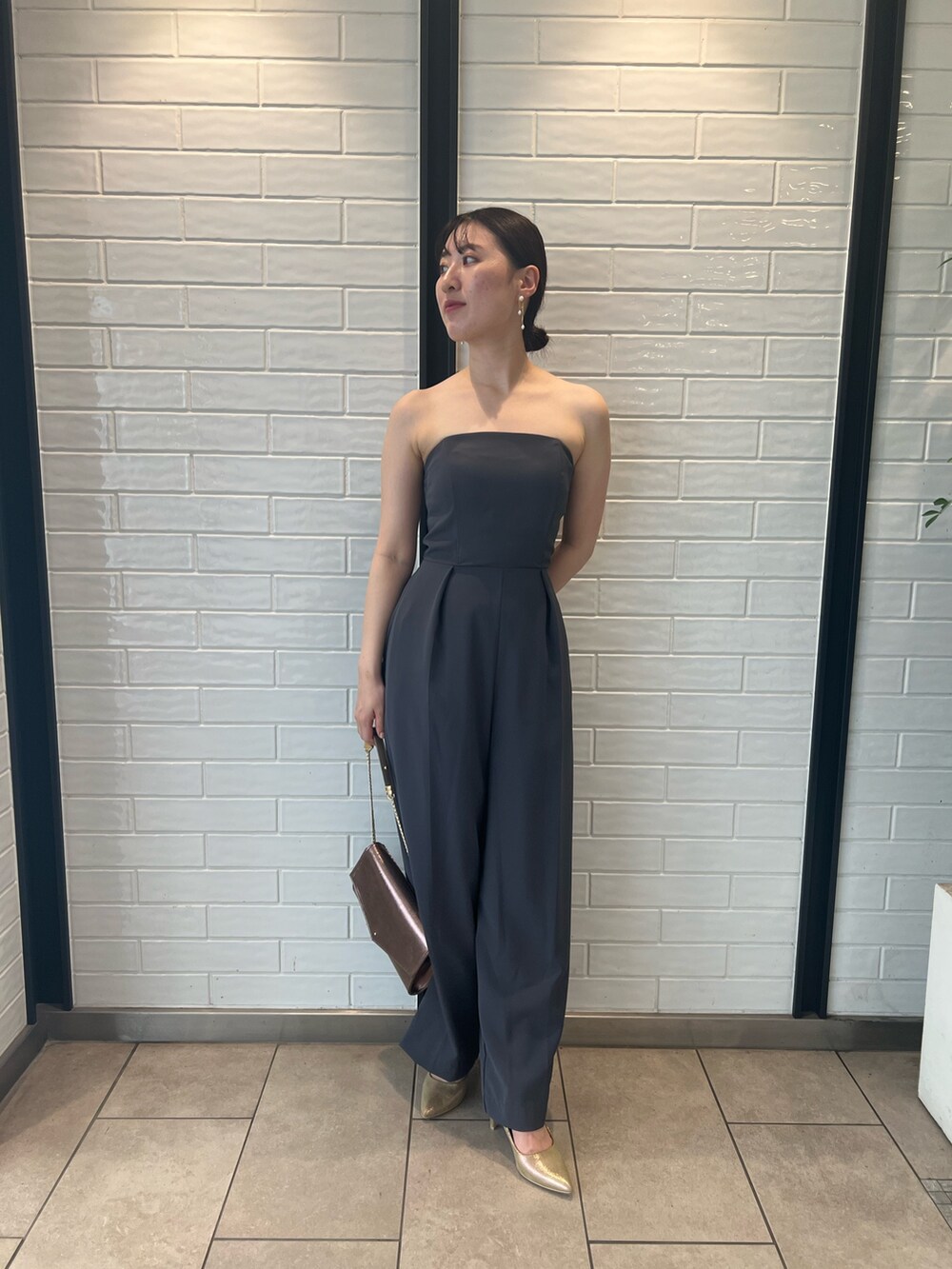 ゴールド系のハンドバッグ、ゴールド系のパンプス、グレー系のパンツドレスを着用したレディースの夏コーディネートの9枚目の写真