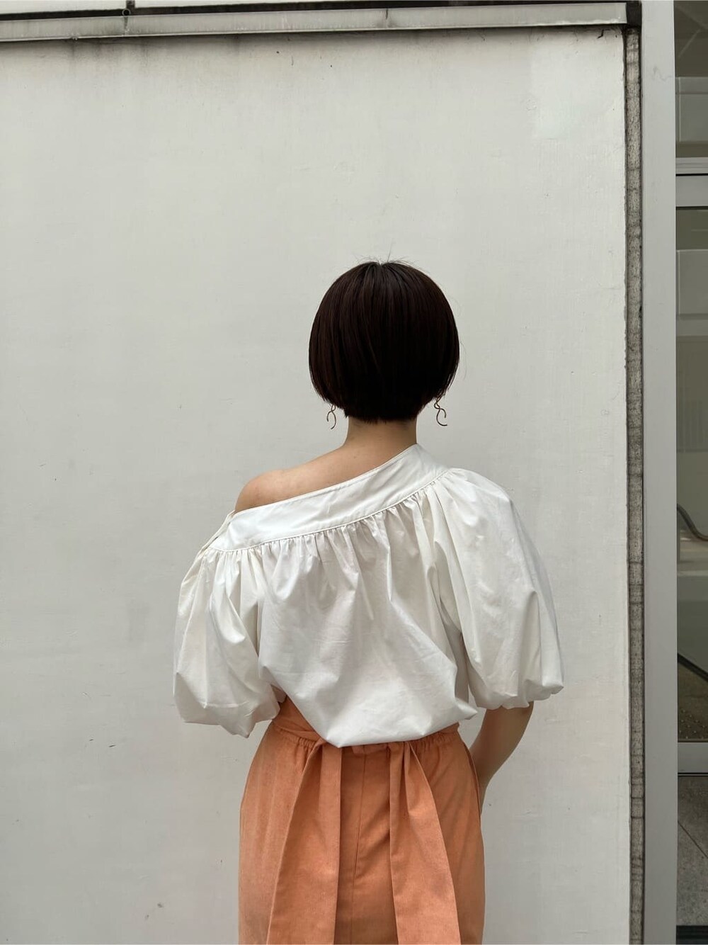 ホワイト系のシャツ/ブラウス、オレンジ系のスカート、ブラウン系のパンプスを着用したレディースの春コーディネートの6枚目の写真