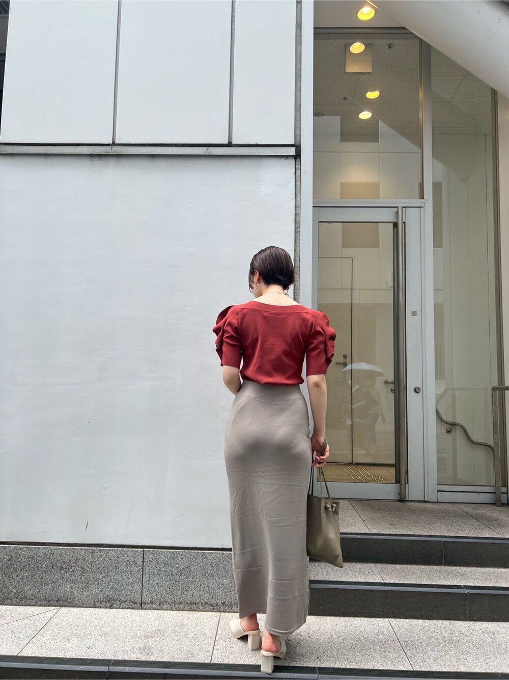 ベージュ系のハンドバッグ、ホワイト系のサンダル、ベージュ系のスカートを着用したレディースの夏コーディネートの3枚目の写真