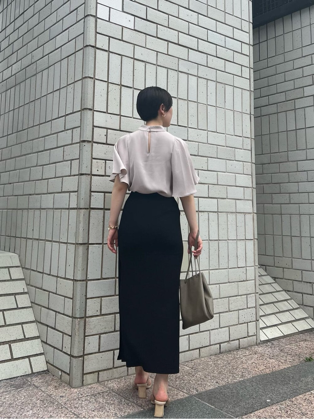 ベージュ系のハンドバッグ、グリーン系のサンダル、ブラック系のスカートを着用したレディースの夏コーディネートの3枚目の写真