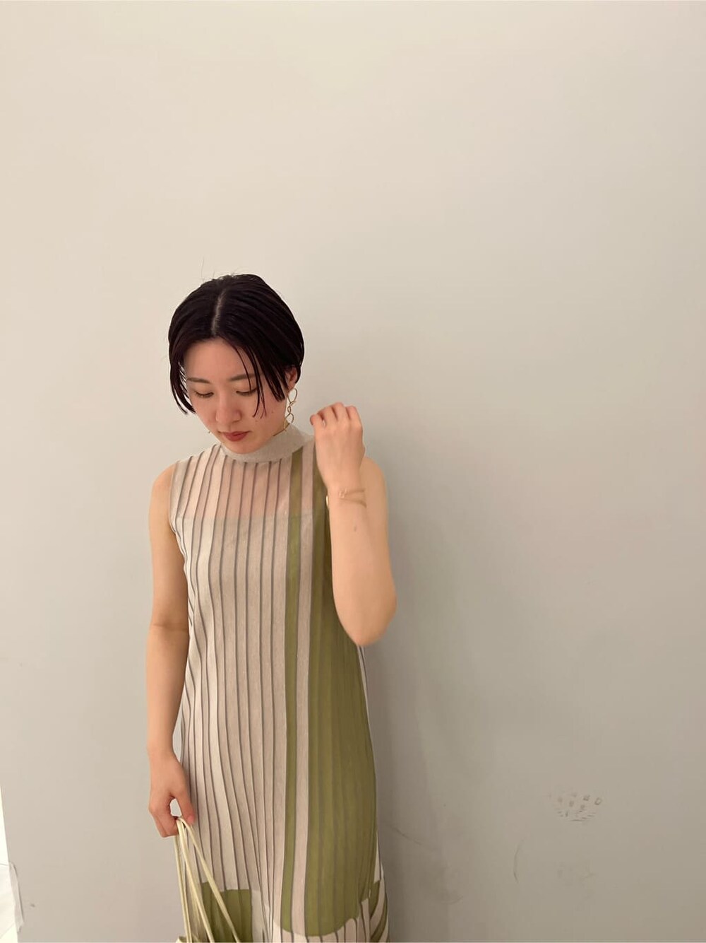 グリーン系のワンピース、グリーン系のサンダル、ゴールド系のピアス（両耳用）を着用したレディースの夏コーディネートの5枚目の写真