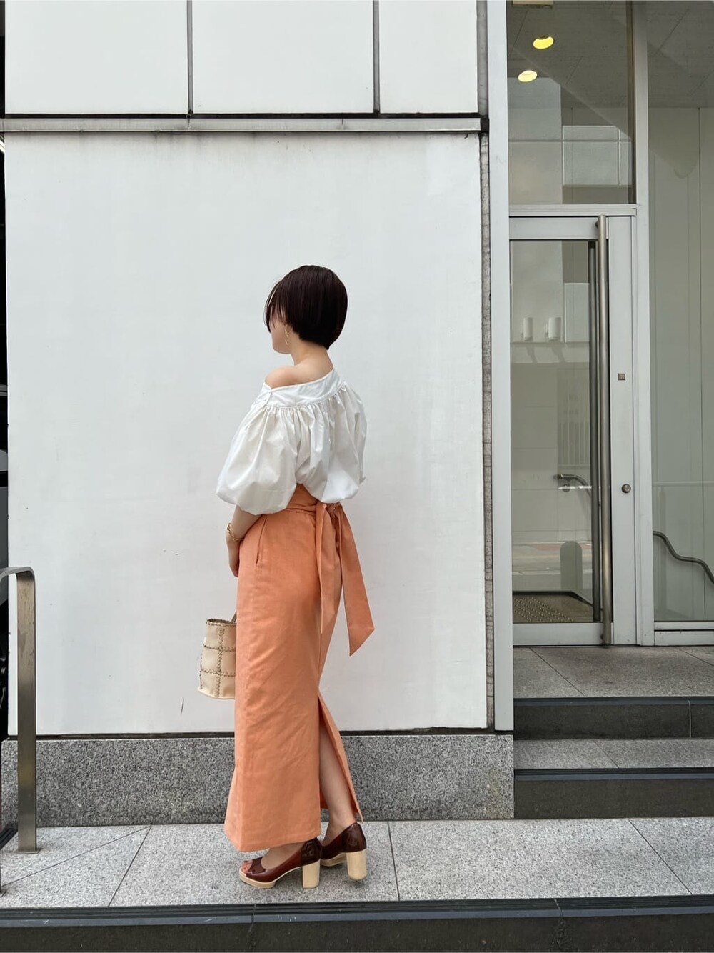 ホワイト系のシャツ/ブラウス、オレンジ系のスカート、ブラウン系のパンプスを着用したレディースの春コーディネートの2枚目の写真