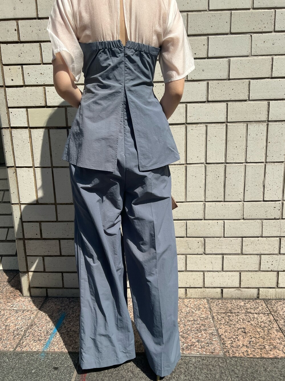 ゴールド系のパンプス、ゴールド系のハンドバッグ、ブルー系のパンツドレスを着用したレディースの春コーディネートの7枚目の写真