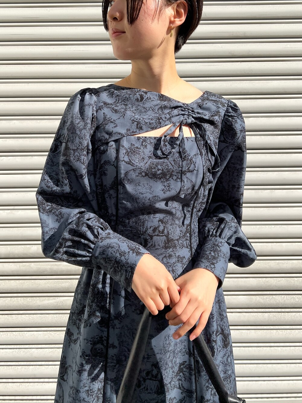 レッド系のブーツ、ブラック系のノーカラーコート、ブルー系のワンピースを着用したレディースの冬コーディネートの4枚目の写真