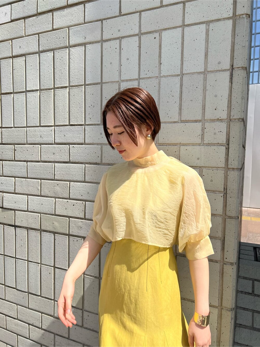 その他のパンプス、イエロー系のワンピース、ゴールド系のバングル/リストバンドを着用したレディースの春コーディネートの4枚目の写真