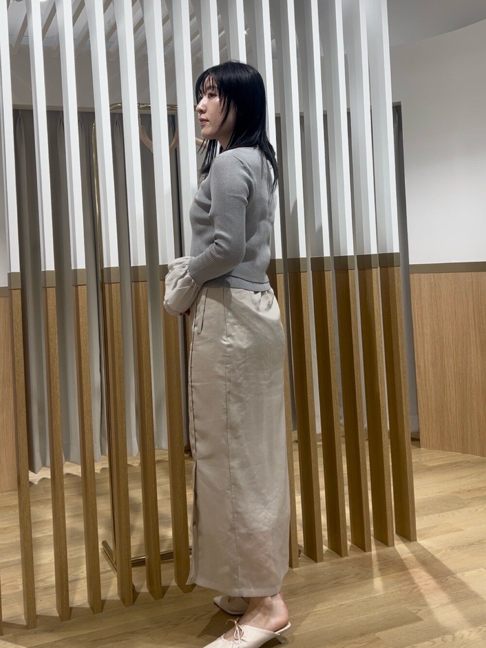 ホワイト系のスカート、グレー系のアンサンブル、ホワイト系のサンダルを着用したレディースの春コーディネートの2枚目の写真