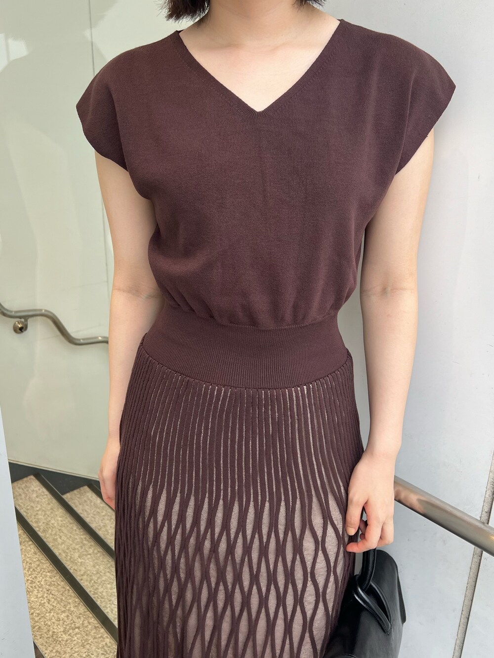 ブラック系のサンダル、ブラック系のハンドバッグ、ブラウン系のワンピースを着用したレディースの夏コーディネートの5枚目の写真