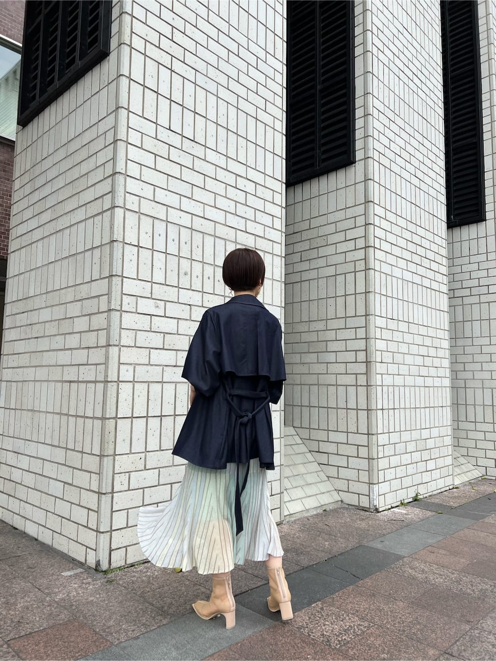 ベージュ系のブーツ、ブルー系のトレンチコート、グリーン系のワンピースを着用したレディースの春コーディネートの4枚目の写真