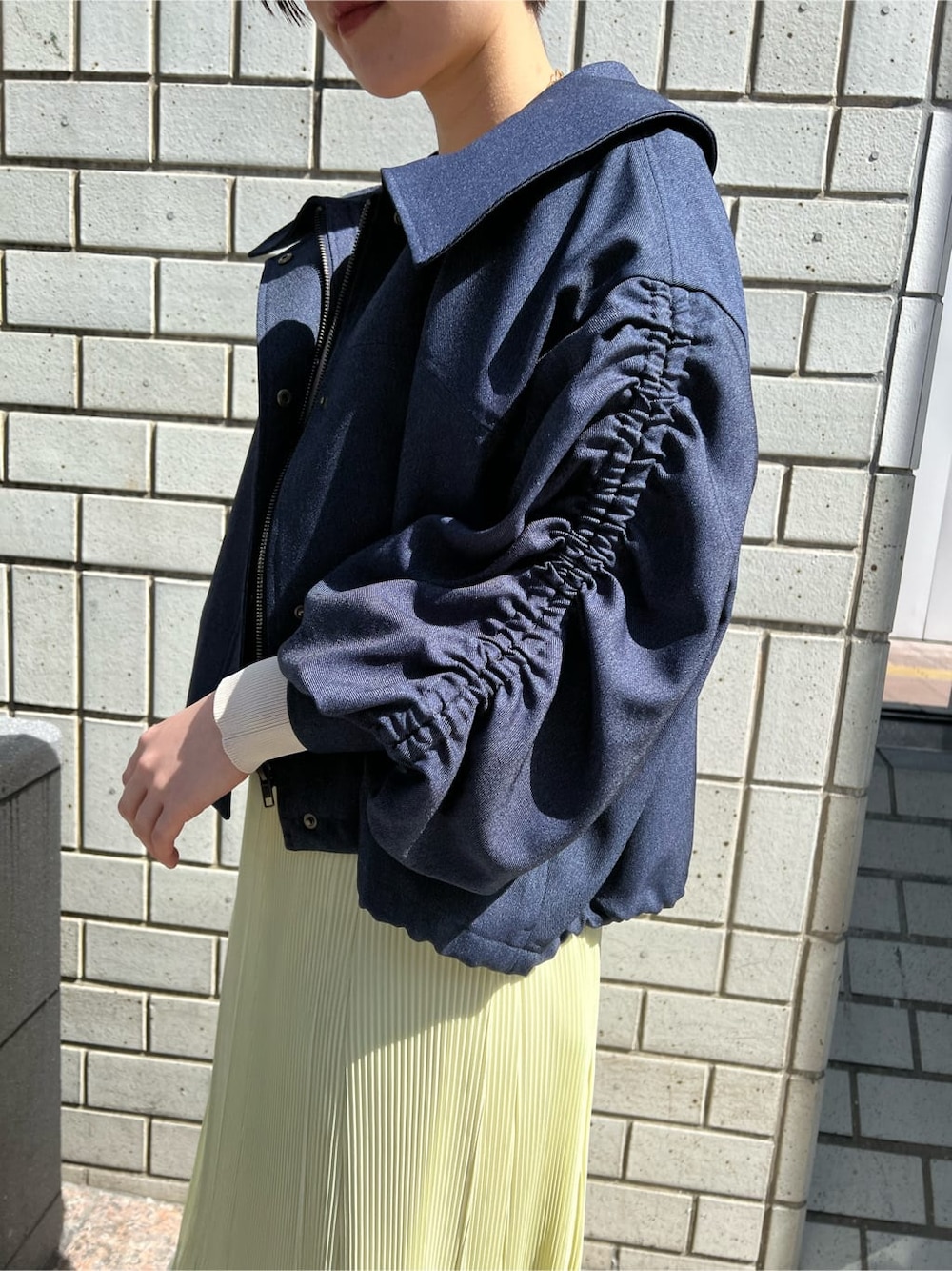 ブルー系のブルゾン、イエロー系のスカート、ベージュ系のニット/セーターを着用したレディースの春コーディネートの4枚目の写真