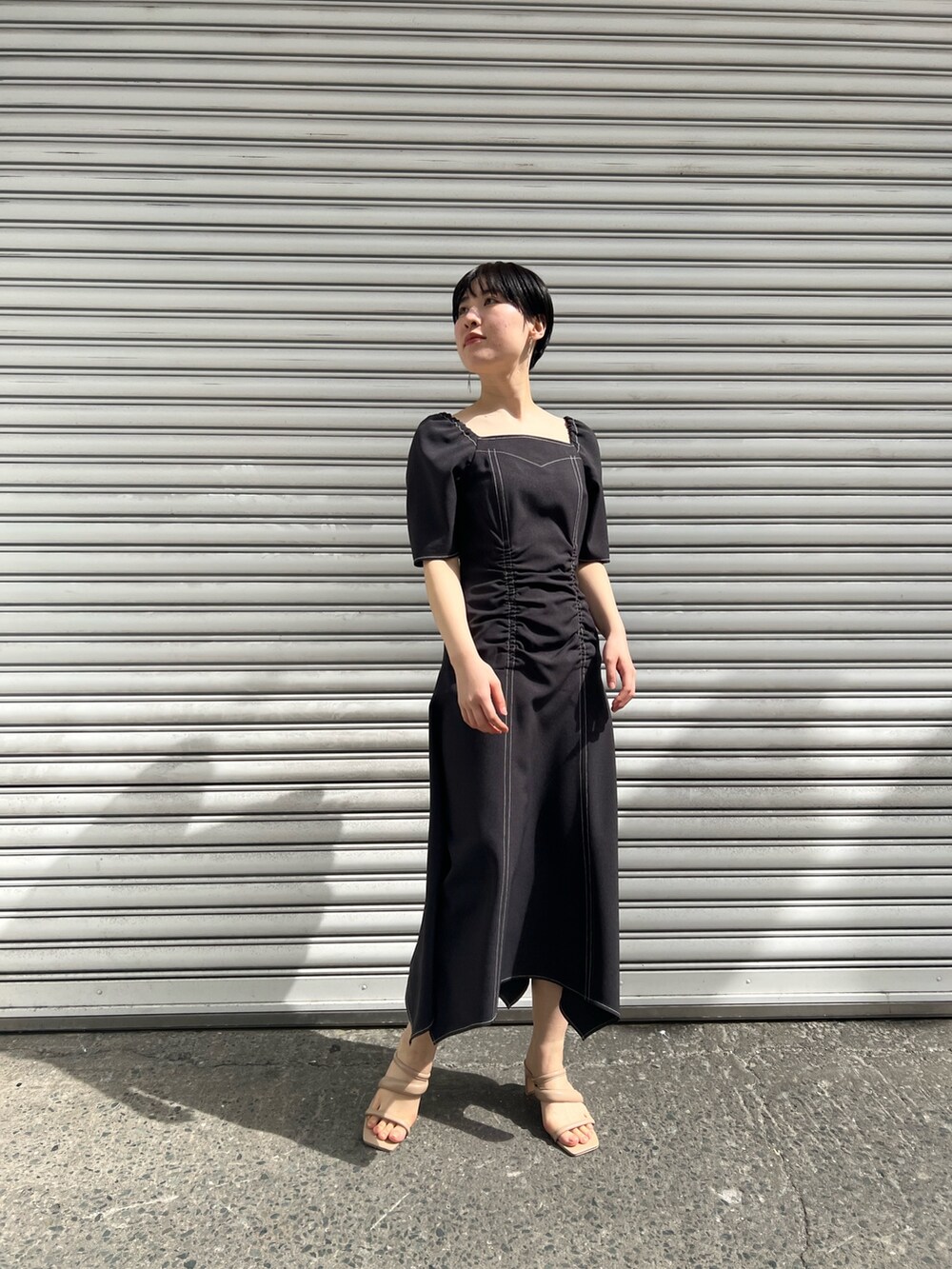 ベージュ系のサンダル、ブラック系のワンピース、ベージュ系のテーラードジャケットを着用したレディースの春コーディネートの3枚目の写真