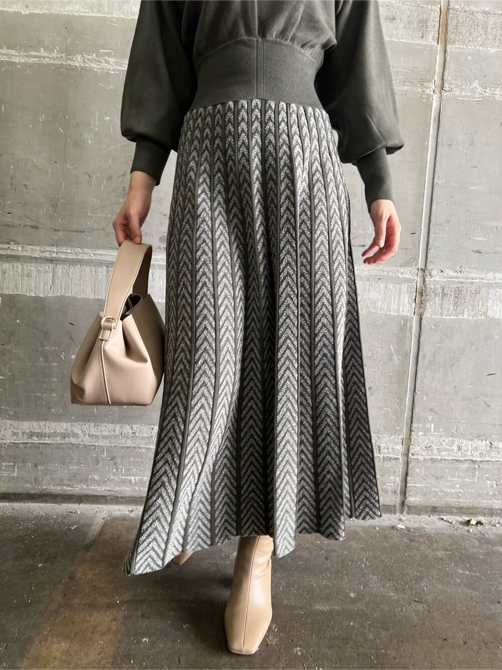 ベージュ系のブーツ、ベージュ系のハンドバッグ、ベージュ系のワンピースを着用したレディースの秋コーディネートの8枚目の写真