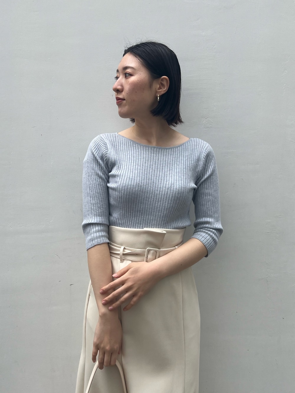 ホワイト系のパンプス、ベージュ系のハンドバッグ、ブルー系のニット/セーターを着用したレディースの春コーディネートの3枚目の写真